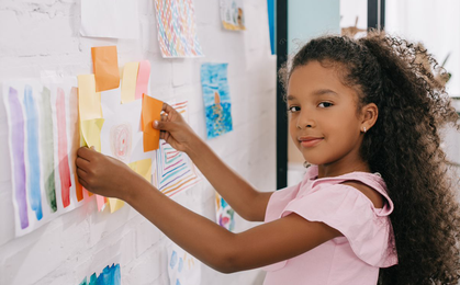 Girl in pink shirt holding yellow and white plastic toy