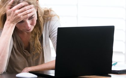 Woman in white shirt sitting beside black laptop computer